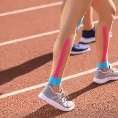 Biegacze na bieżni z kolorowymi taśmami na nogach. Kinesiotaping przeciwwskazania - warto pamiętać o nich przed zastosowaniem.