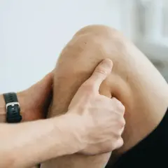 Fizjoterapeuta bada kolano, szukając odpowiedzi, co na bolące kolana.