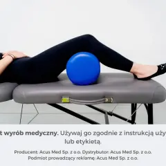 Fizjoterapia przy rwie kulszowej: niebieska piłka pod plecami pacjentki na kozetce.