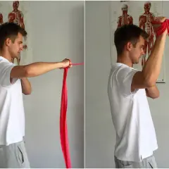 Ćwiczenia z gumą na barki. Mężczyzna wykonuje ruchy ramionami, co może pomóc w problemach z przeskakiwaniem w barku.