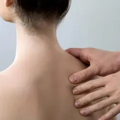 Fizjoterapeuta bada plecy pacjentki, szukając oznak złamania łopatki.