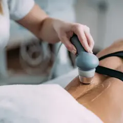 Fizjoterapeuta wykonuje zabieg ultradźwiękami rehabilitacja na plecach pacjentki.