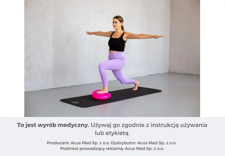 Kobieta wykonuje ćwiczenia równowagi na różowej poduszce sensorycznej, stojąc na macie.