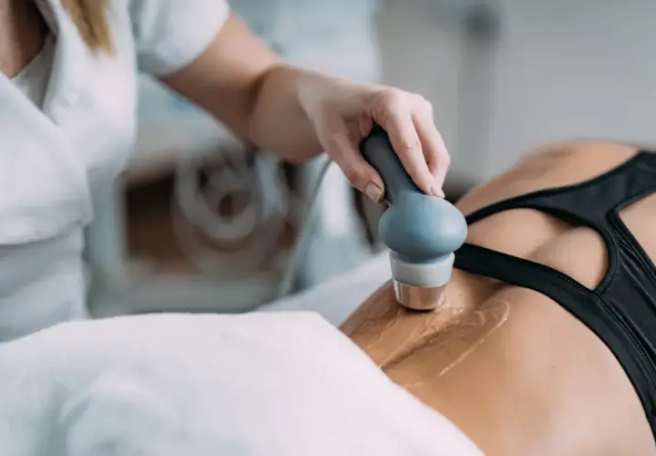 Fizjoterapeuta wykonuje zabieg ultradźwiękami rehabilitacja na plecach pacjentki.