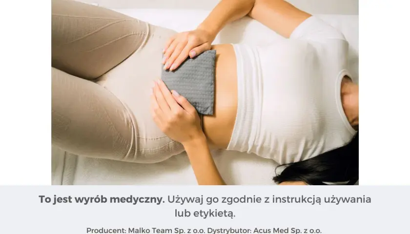 Kobieta z termoforem na brzuchu. Pamiętaj o instrukcji, by uniknąć skutków ubocznych termoforu.