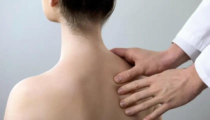 Fizjoterapeuta bada plecy pacjentki, szukając oznak złamania łopatki.