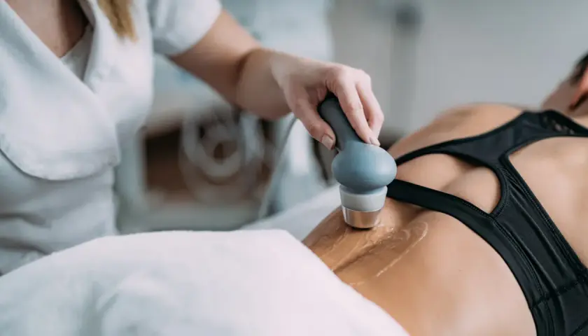 Fizjoterapeuta wykonuje zabieg ultradźwiękami rehabilitacja na plecach pacjentki.