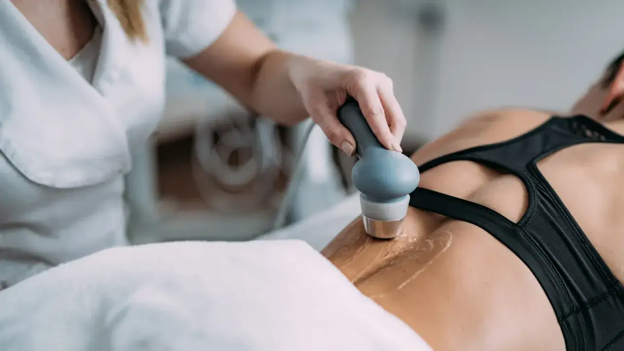 Fizjoterapeuta wykonuje zabieg ultradźwiękami rehabilitacja na plecach pacjentki.