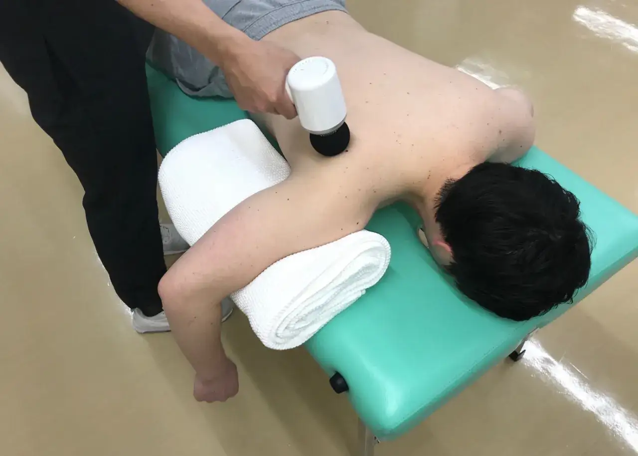 Fizjoterapeuta wykonuje masaż wibracyjny pleców. Choć zazwyczaj przynosi ulgę, warto znać potencjalne masaż wibracyjny skutki uboczne.