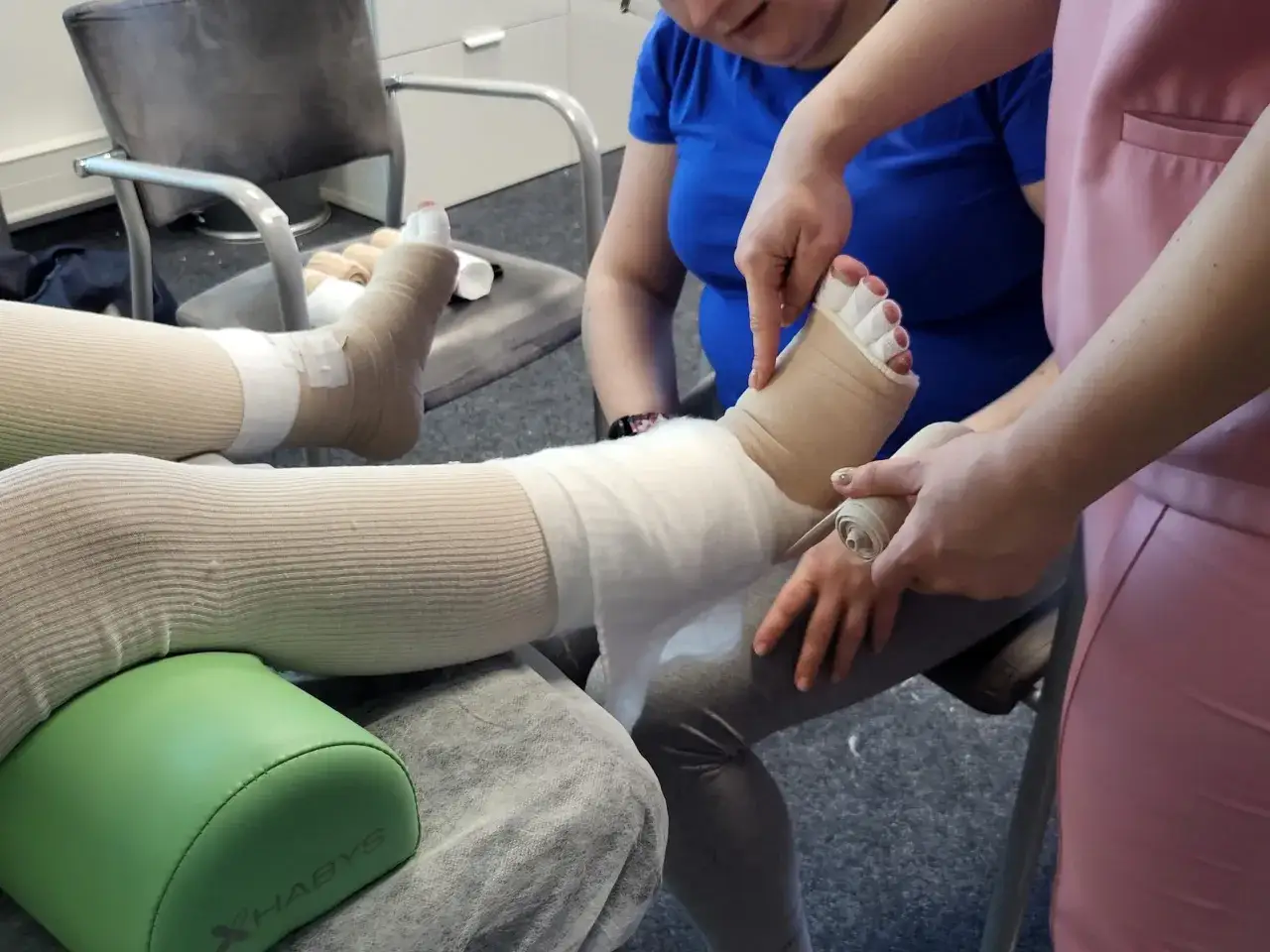 Terapia uciskowa nóg, kluczowa w walce z obrzękiem limfatycznym. Specjalistka bandażuje stopę i łydkę, by usprawnić przepływ limfy.