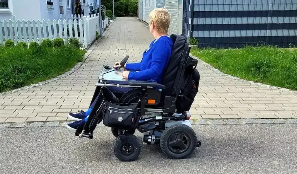 osoba na wózku inwalidzkim na chodniku
